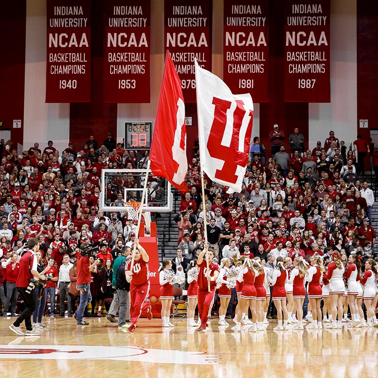 Male and female cheerleaders run IU flags on the court at Assembly Hall. 