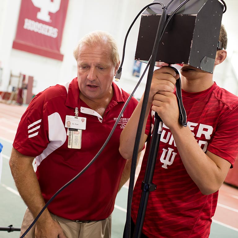 Nicholas Port assists a student athlete in using his concussion detecting device.